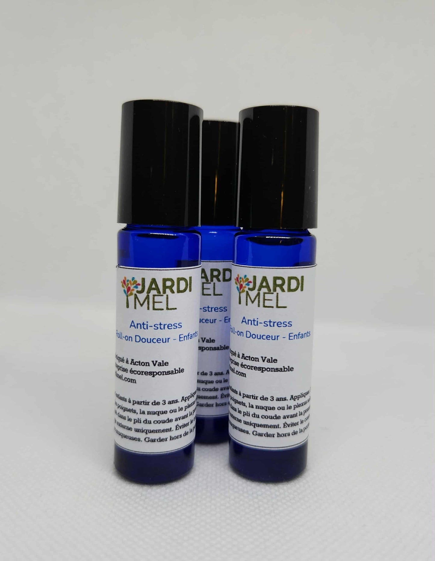 Trois flacons bleus de roll-on « Anti-stress » pour enfants de la marque Jardi Mel, disposés côte à côte sur un fond blanc. Les étiquettes indiquent qu’il s’agit d’un produit naturel et écoresponsable fabriqué à Acton Vale.