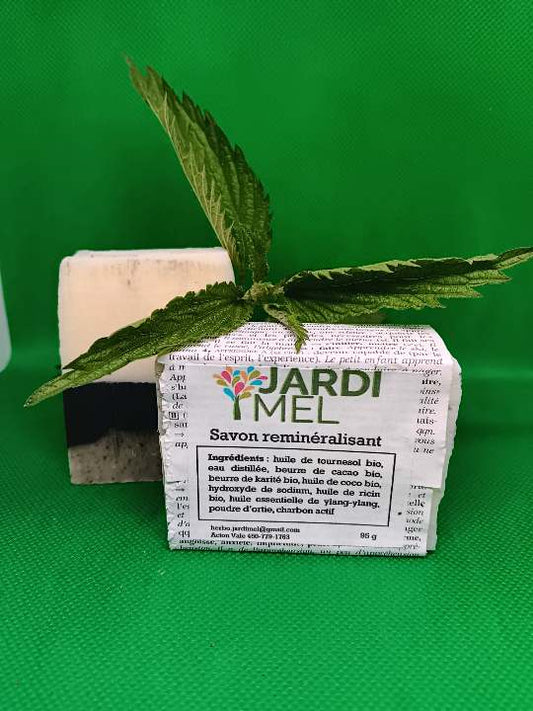 Savon artisanal "Savon reminéralisant" de JARDI MEL, emballé avec une feuille de dictionnaire, feuille naturelle d'ortie en décoration, étiquette listant des ingrédients naturels et bio et indiquant jardimel.com